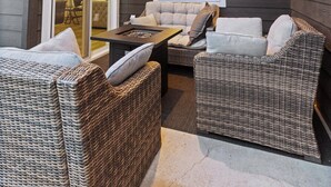 A covered patio area with wicker furniture, a glass door leading to an interior space, and string lights on the ceiling. - Coeur d'Alene Townhome Modern New Downtown Shops Beach (CDA)