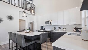 A modern kitchen with white cabinets, a central island, and bar stools. - Coeur d'Alene Townhome Modern New Downtown Shops Beach (CDA)