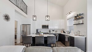 A modern kitchen with a central island, bar stools, and a dining area with a sofa. - Coeur d'Alene Townhome Modern New Downtown Shops Beach (CDA)