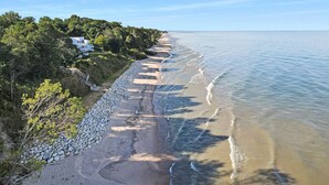 A coastal property with a paved walkway along the beach, a stone wall, and a house with a view of the sea.