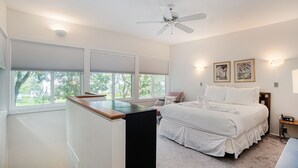 A bedroom with a bed, a desk, a ceiling fan, and two wall-mounted lights.