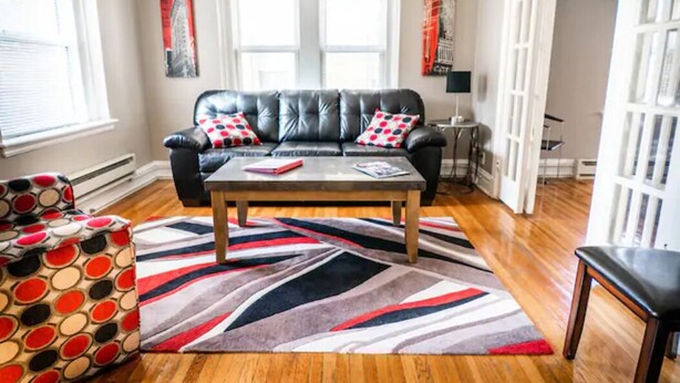 A living room with a leather sofa, a patterned armchair, a coffee table, and a striped rug.
