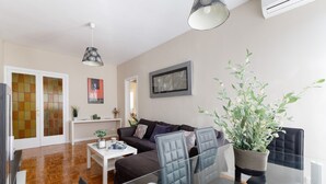 En moderne stue med et glasbord, læderstole, en sofa og en potteplante.
