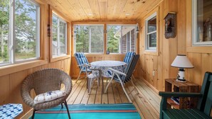 A wooden-paneled room with a round table, chairs, and a wicker chair. - Easy Bike Path Access, Dog Welcome! (Chatham)