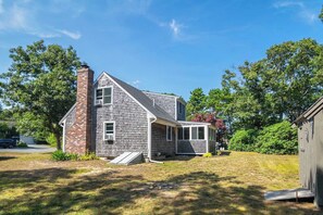 A two-story house with a brick chimney, a covered porch, and a small shed. - Easy Bike Path Access, Dog Welcome! (Chatham)