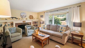 A cozy living room with a fireplace, two sofas, a coffee table, and a television. - Easy Bike Path Access, Dog Welcome! (Chatham)