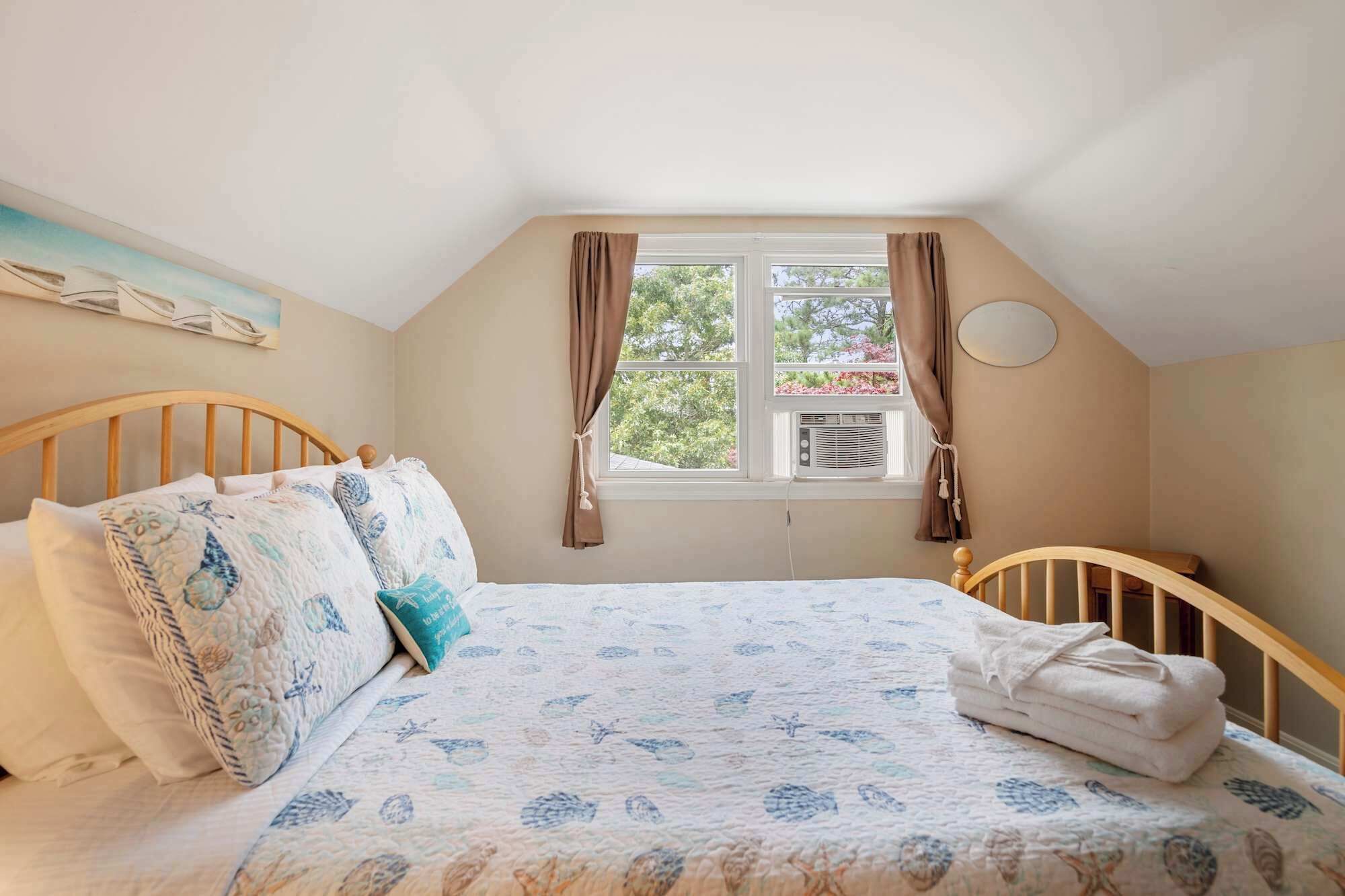 A bedroom with a bed, a window, and a wall-mounted air conditioner.