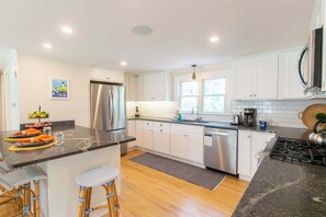 A modern kitchen with white cabinetry, a stainless steel refrigerator, a built-in dishwasher, and a gas stove.