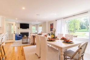 A dining area with a table set for two, a fireplace, and a television in the background.