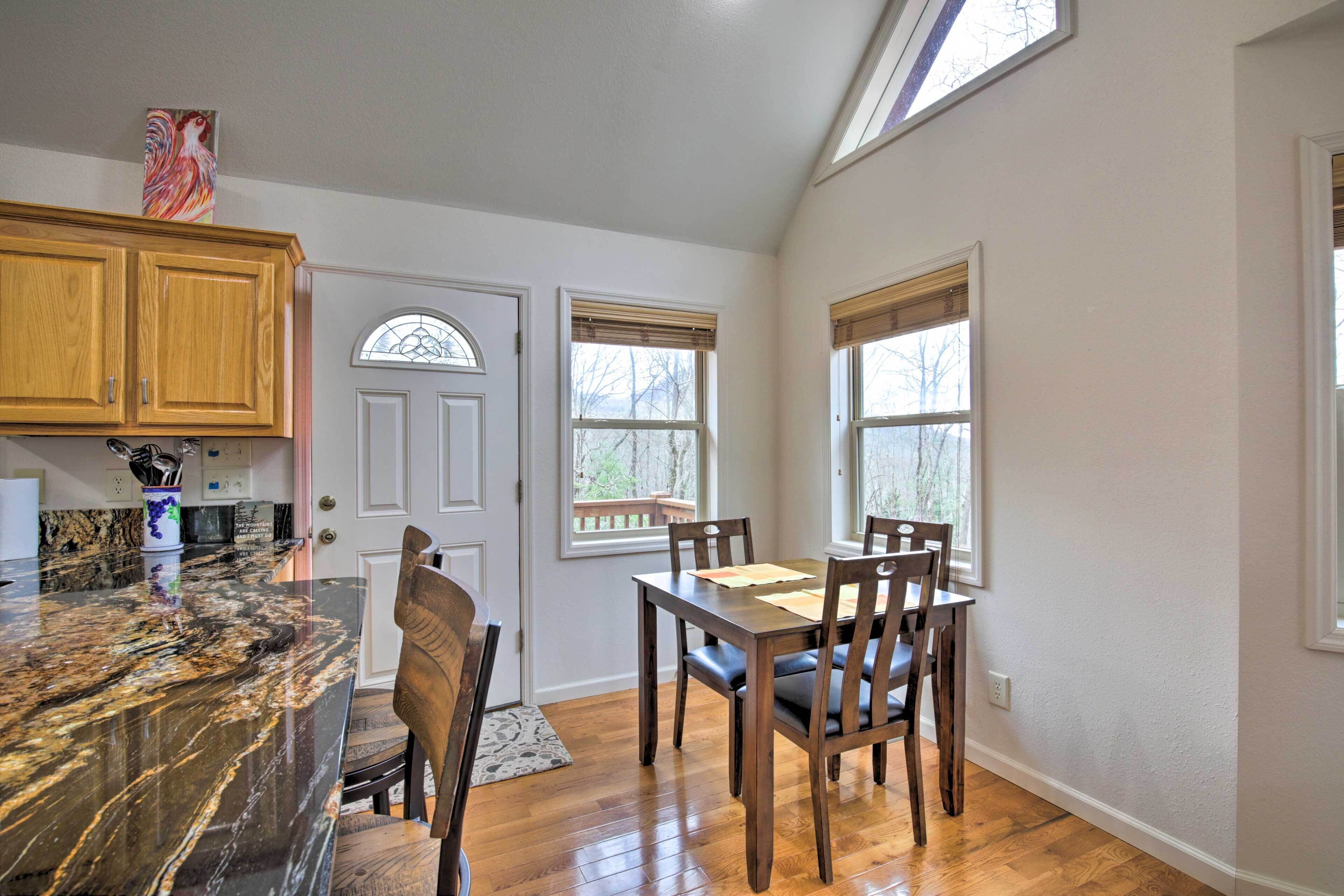A kitchen with wooden cabinets, a marble countertop, and a dining area with a table and chairs.