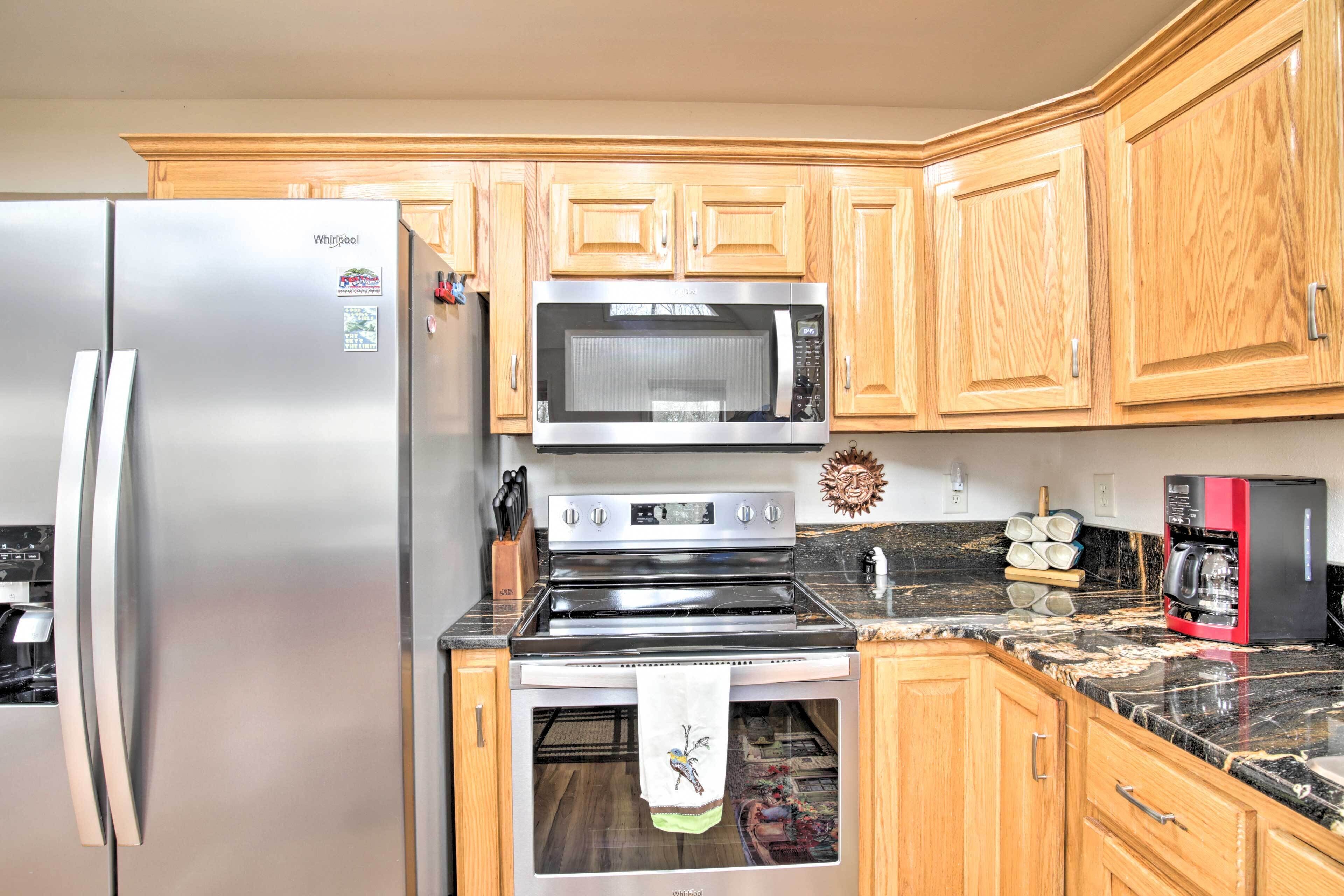 A kitchen with wooden cabinets, a stainless steel refrigerator, a microwave, an oven, and a coffee maker.