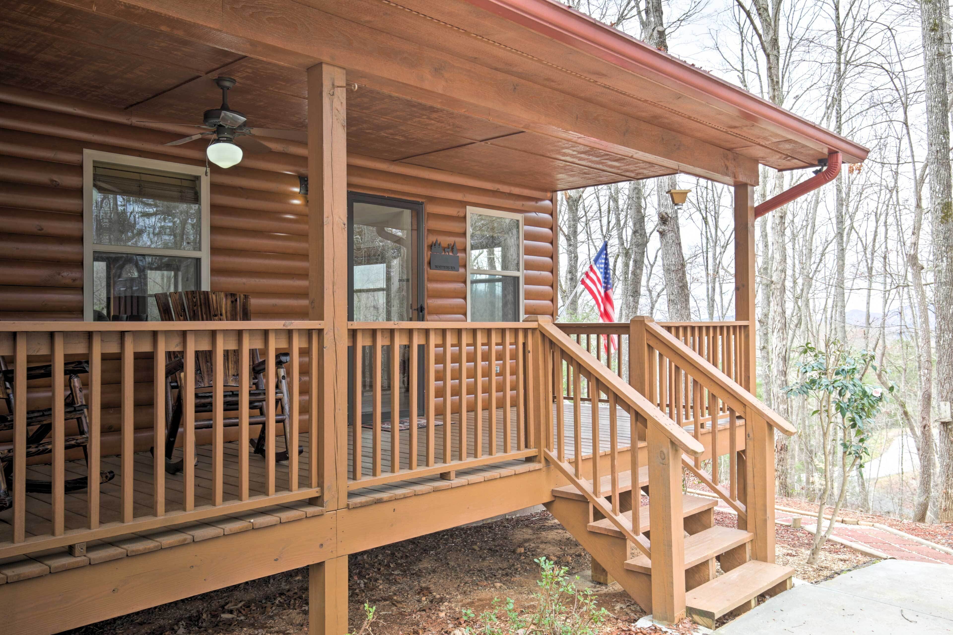 A wooden cabin with a porch, a staircase, and a flag.