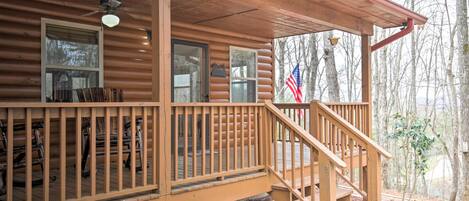 A wooden cabin with a porch, a staircase, and a flag.