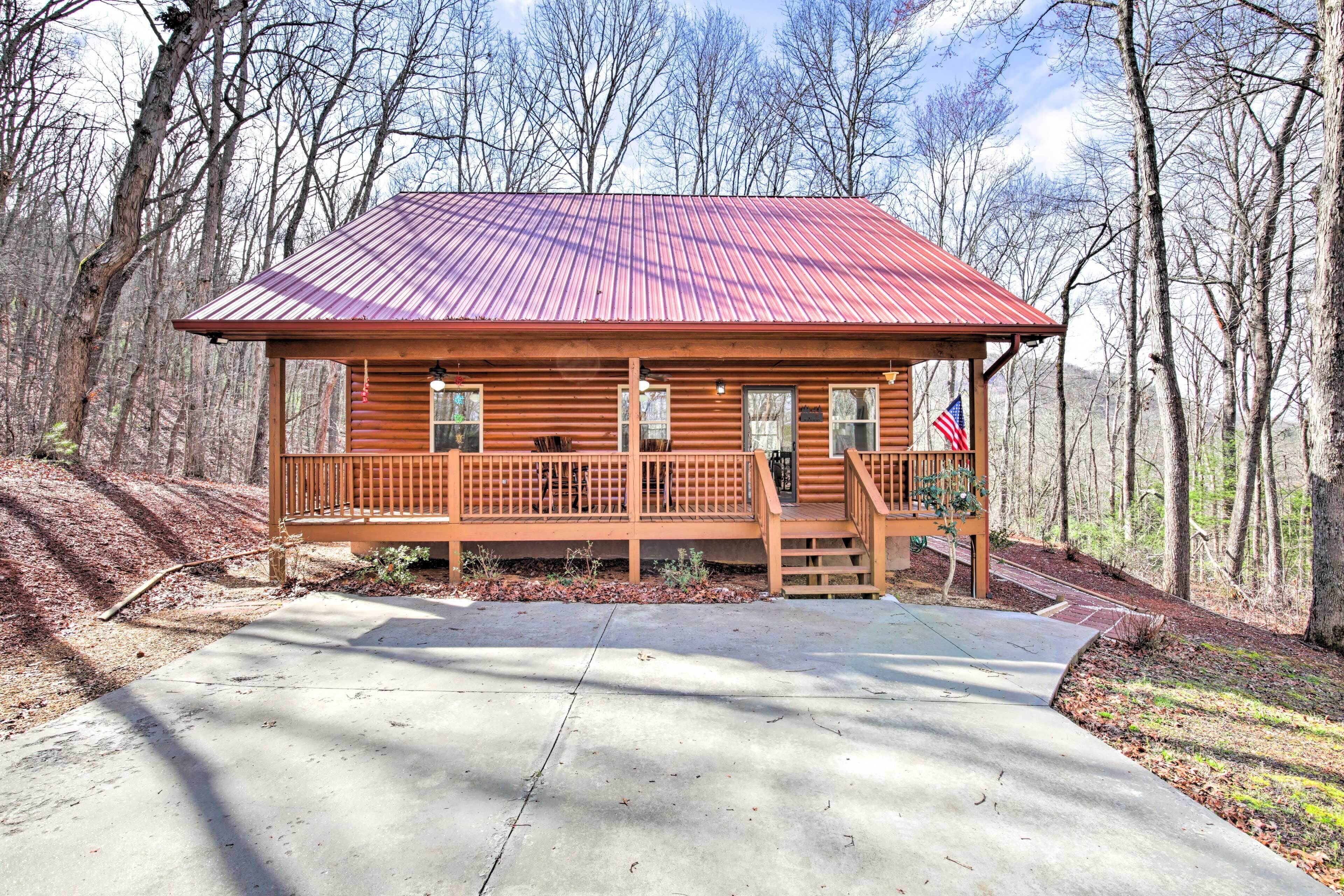 A wooden cabin with a metal roof, a porch, and a flag.