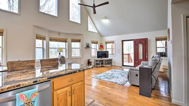 A spacious living area with a kitchen island, wooden cabinets, and a large window. - Cozy Hayesville Retreat w/ Deck & Mtn Views! (Hayesville)