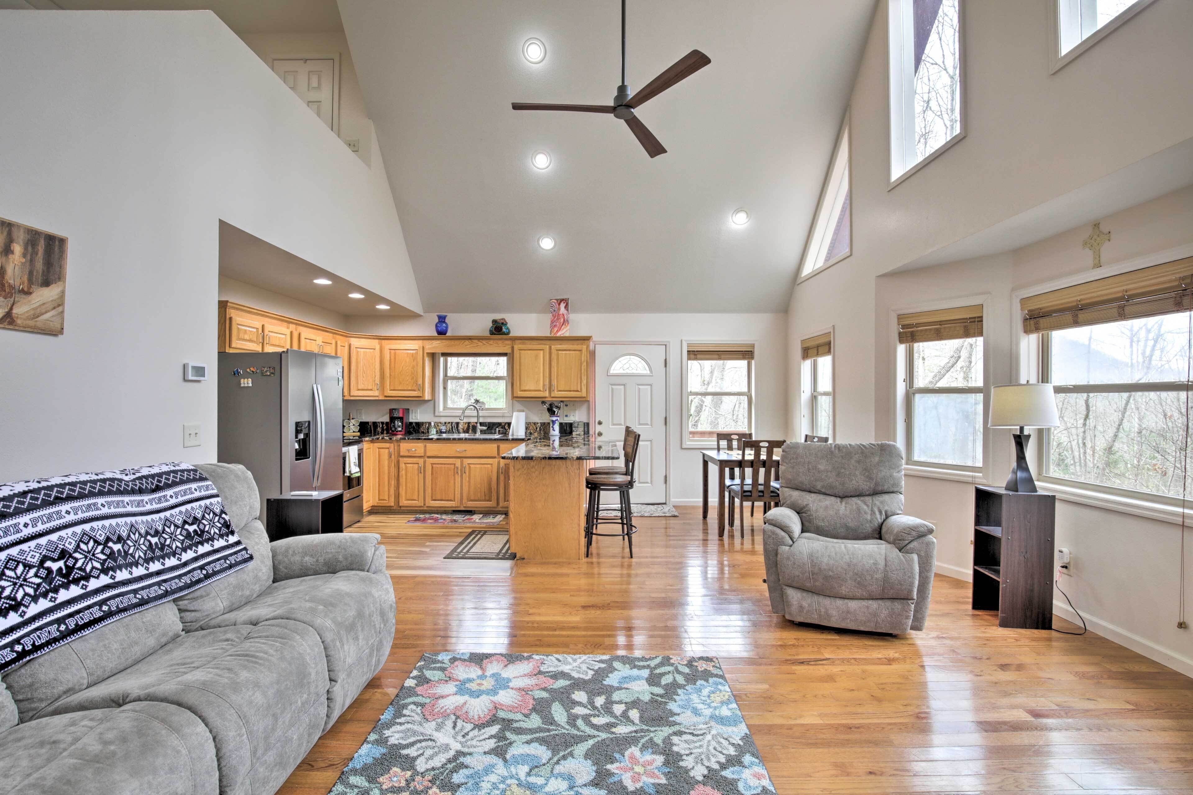 A spacious living room with a gray sofa, a floral rug, and a ceiling fan.