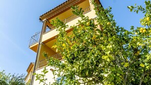 Un edificio de varios pisos con balcones y un árbol en primer plano.