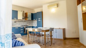 Una cocina compacta con armarios azules, una mesa de comedor con sillas y un refrigerador blanco.