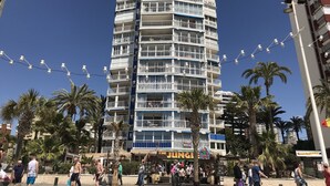 Ein mehrstöckiges Hotel mit Balkonen, direkt am Strand gelegen, und ein Schild für das Restaurant 'The Jungle'.