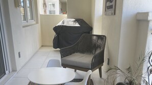 Terassialue, jossa on rottinkihuonekaluja, katettu grilli ja kuvioitu matto.