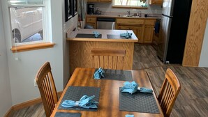 A modern kitchen with wooden cabinets, a central island, and a dining area with a wooden table and chairs. - Lakefront Home/Amazing Lake View/Pomme Paradise #2 (Pittsburg)