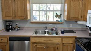 A kitchen with wooden cabinets, a stainless steel sink, a dishwasher, and a stove. - Lakefront Home/Amazing Lake View/Pomme Paradise #2 (Pittsburg)