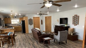 A spacious living area with a sofa, chairs, a dining table, and a kitchen in the background. - Lakefront Home/Amazing Lake View/Pomme Paradise #2 (Pittsburg)