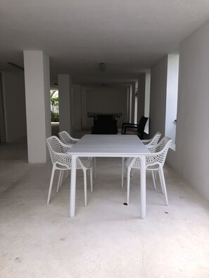 A spacious room with a large white table and four white chairs, a dark-colored sofa, and a small black table in the background. - Jungle vibe,  with  Sea side breezes , EXPERIENCE THE MAYAN RIVIERA  (Akumal)