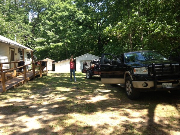 A campsite with a wooden deck, a black pickup truck, and a small shed.