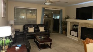 Una sala de estar con un sofá modular, una mesa de centro, un televisor y una chimenea.