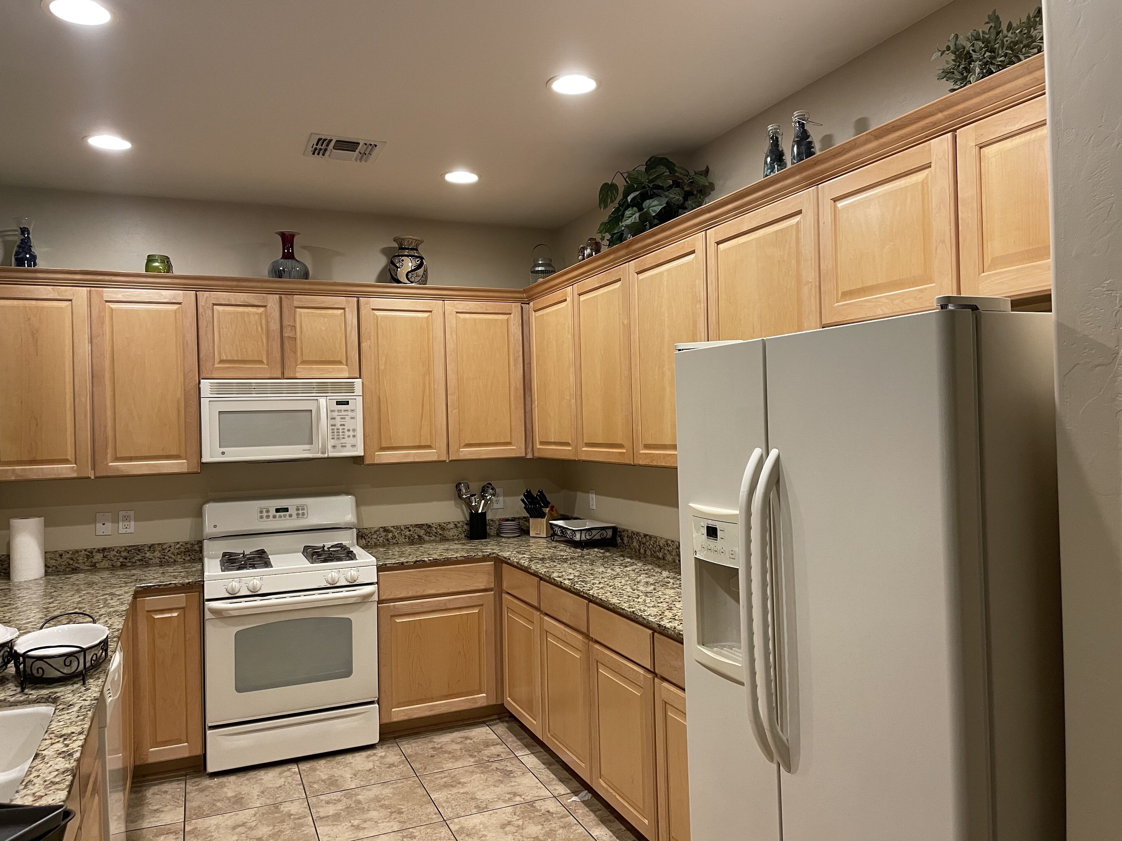 A kitchen with wooden cabinets, a white refrigerator, a microwave, and a stove.