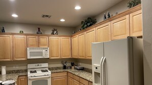 Una cocina con armarios de madera, un refrigerador blanco, un microondas y una estufa.