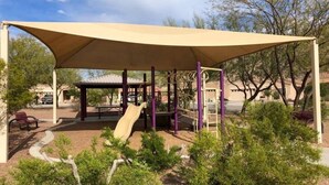 Un parque infantil con una pérgola, toboganes y estructuras para escalar.