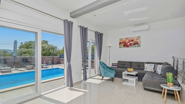 A modern living room with a pool, grey curtains, a grey sofa, and a painting on the wall. - Holiday house Pink with Pool (Skrbčići)