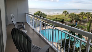 A balcony with a view of a beach and a swimming pool. - Quiet second floor Beachfront Condo with two bedrooms and a sleeper sofa. (Myrtle Beach)