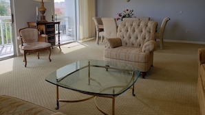 A living room with a glass coffee table, two armchairs, a sofa, a lamp, and a chandelier. - Quiet second floor Beachfront Condo with two bedrooms and a sleeper sofa. (Myrtle Beach)