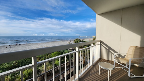 A balcony with a view of the beach, a chair, and a small table. - Quiet second floor Beachfront Condo with two bedrooms and a sleeper sofa. (Myrtle Beach)
