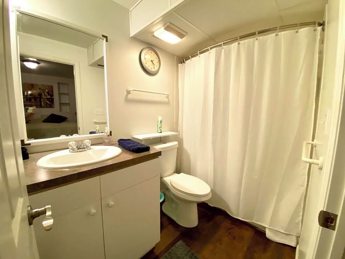 Un baño con lavamanos, inodoro y cortina de ducha.
