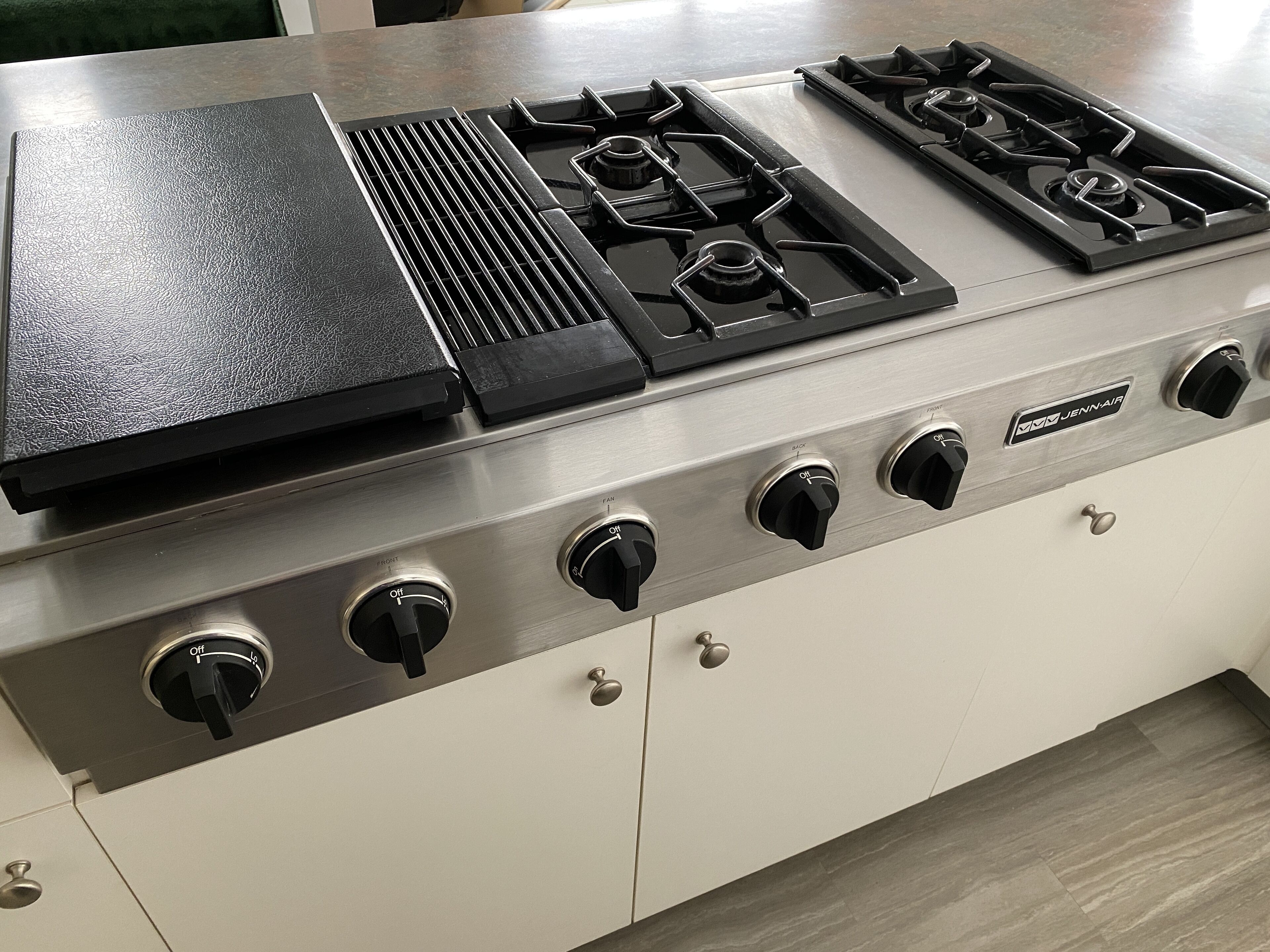 A kitchen with a stainless steel stove, four burners, and a griddle.