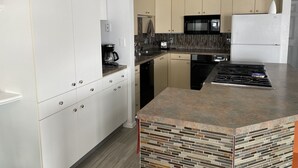 A modern kitchen with white cabinets, a granite countertop, a built-in stove, and a microwave.