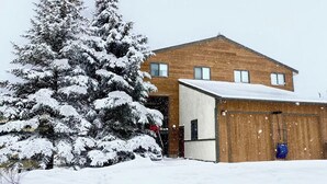 A two-story building with a snow-covered roof and a garage attached to the right side.