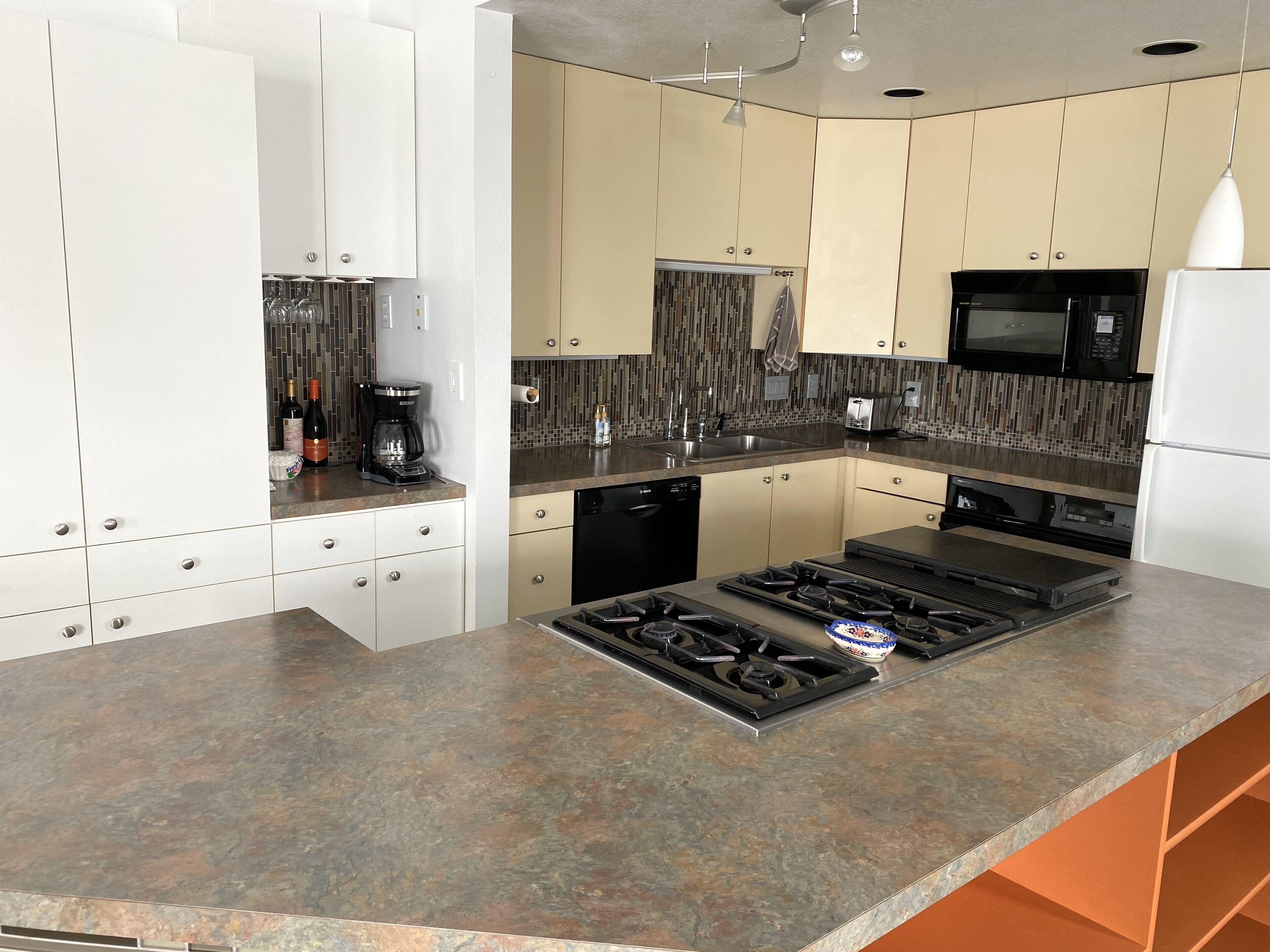 A modern kitchen with white cabinets, a built-in stove, a microwave, and a dishwasher.
