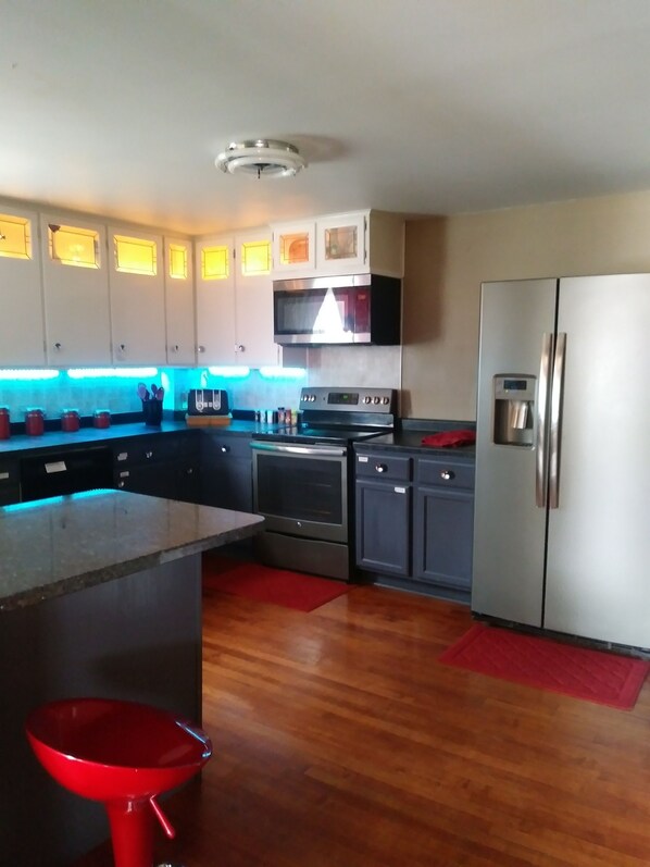 Una cocina moderna con electrodomésticos de acero inoxidable, piso de madera e una isla central.