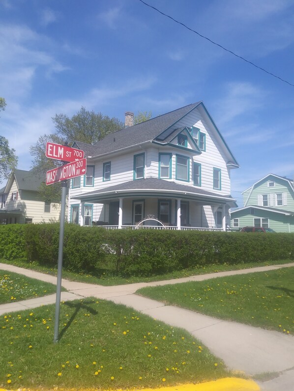 A large, two-story house with a porch and a white exterior.