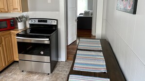 A kitchen with wooden cabinets, a microwave, an oven, and a painting on the wall.