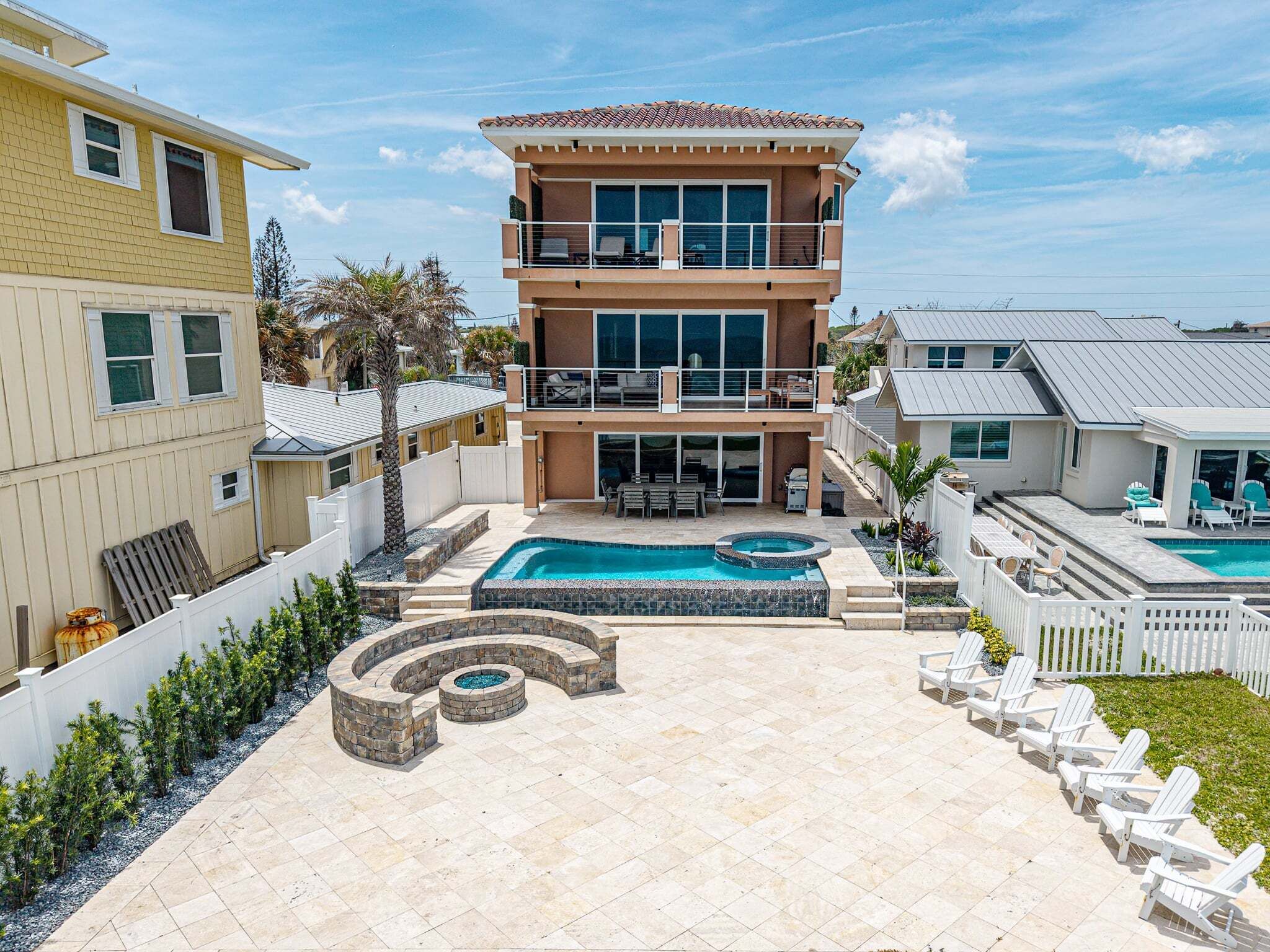 A two-story house with a swimming pool, outdoor seating, and a fenced yard.