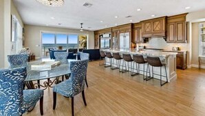 A spacious kitchen with a large island, bar stools, and a dining area with a glass table.