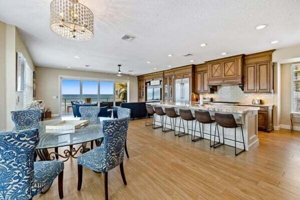 A spacious kitchen with a large island, bar stools, and a dining area with a glass table.