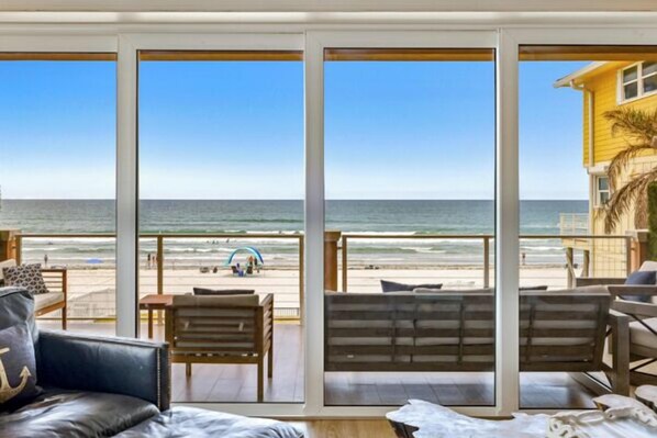 A balcony with a view of the beach, a wooden bench, and a sofa.