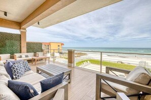 Un balcón con mobiliario exterior que da a una playa y el océano.